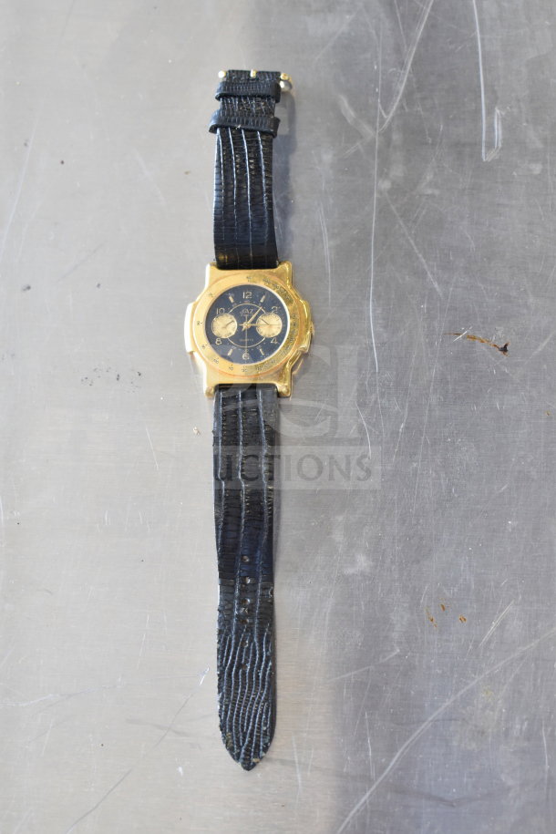 Gold-tone watch with black textured strap, dual dials, fair condition. Plexiglass face, visible wear on strap and case.