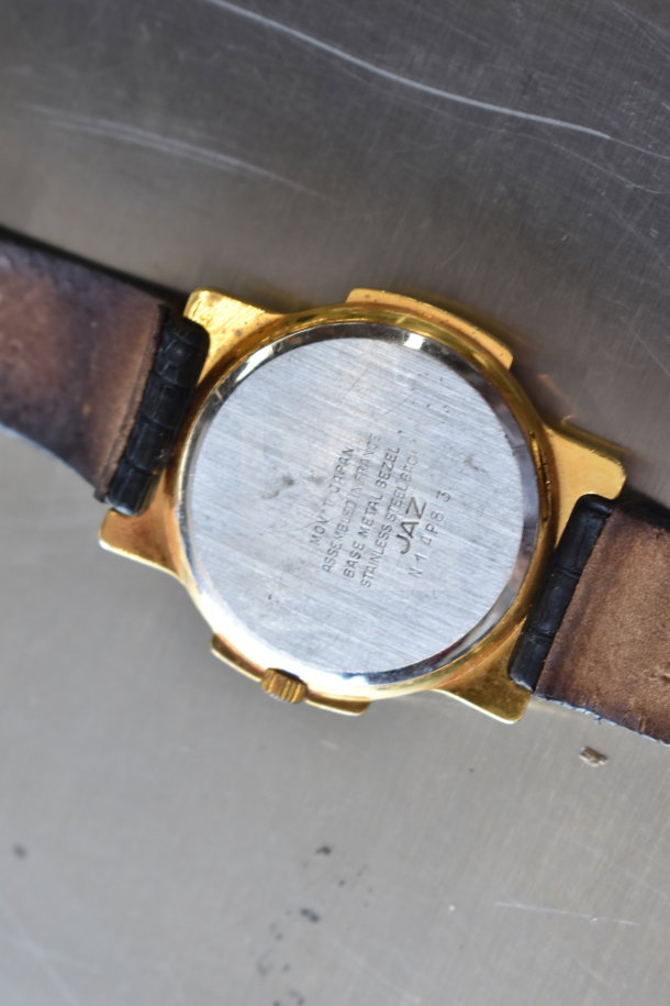 Back view of a vintage Jaz wristwatch with a leather strap and gold-tone bezel. Markings indicate stainless steel back.