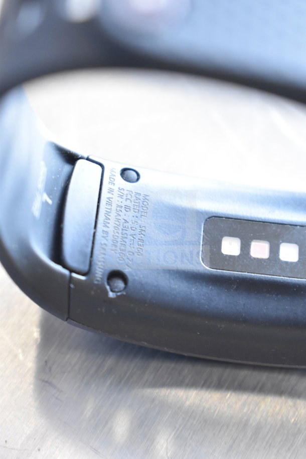 Black fitness watch close-up showing model number SM-R360 and manufacturing details by Samsung, made in Vietnam.
