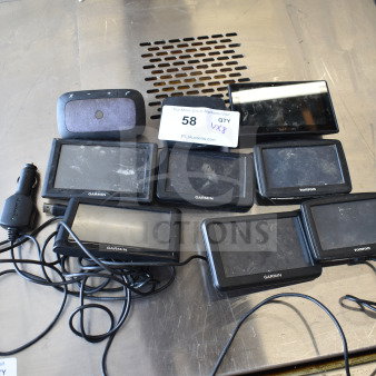 8 assorted GPS devices, including Garmin and TomTom models, with chargers. Dusty condition, lot of 8 items.