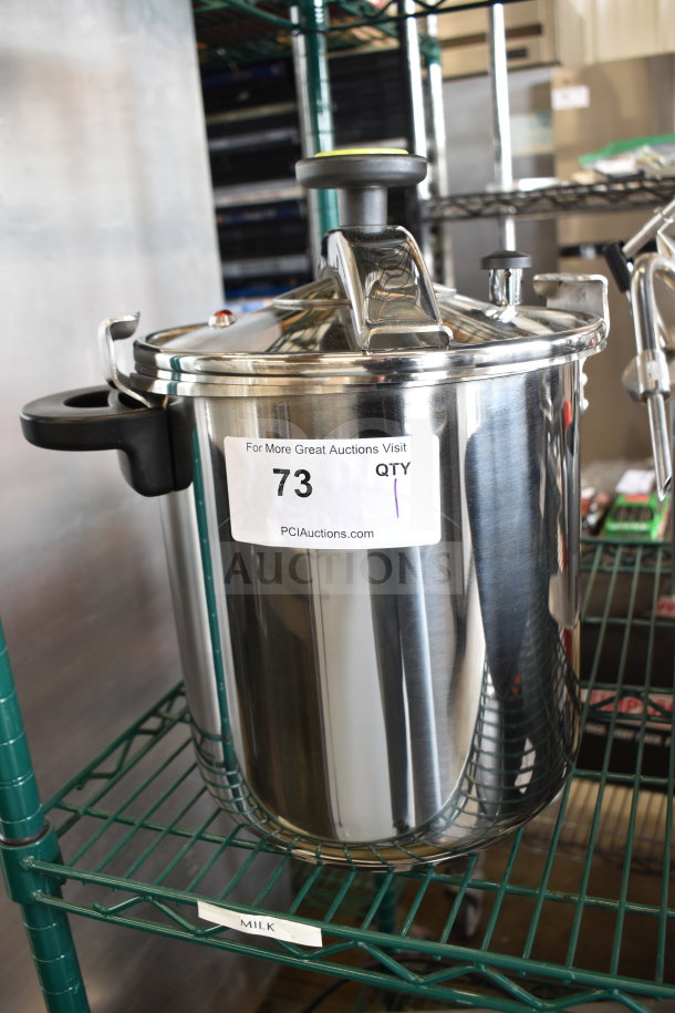 Brand new Monix Pressure Pot, stainless steel, visible scratch and dent, with secure lid and black handles. Auction tag labeled "73".