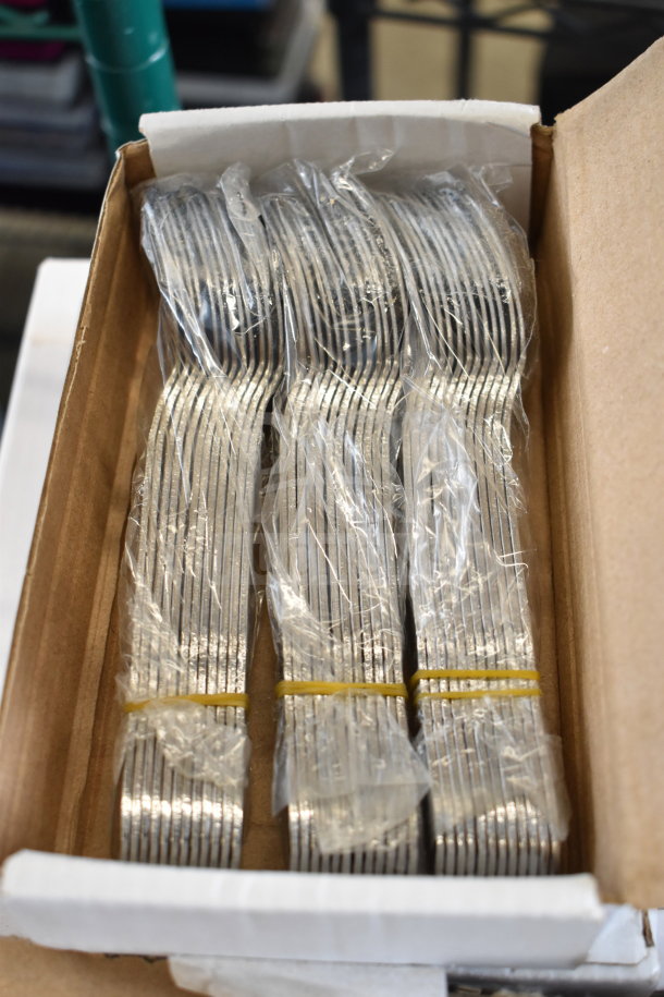 Box of multiple unused metal drain strainers, each still in plastic and bundled with rubber bands, shown in open box.