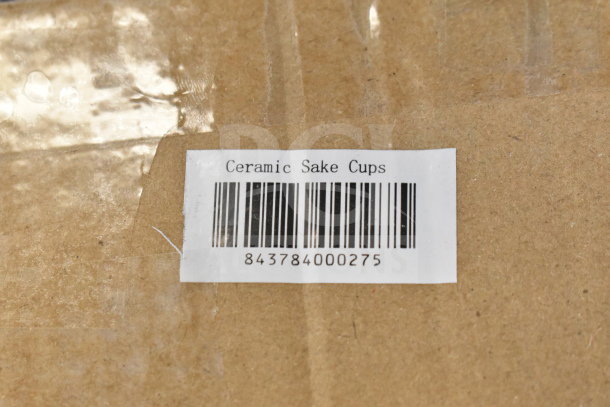 Cardboard box with label reading "Ceramic Sake Cups" and barcode 843784000275.