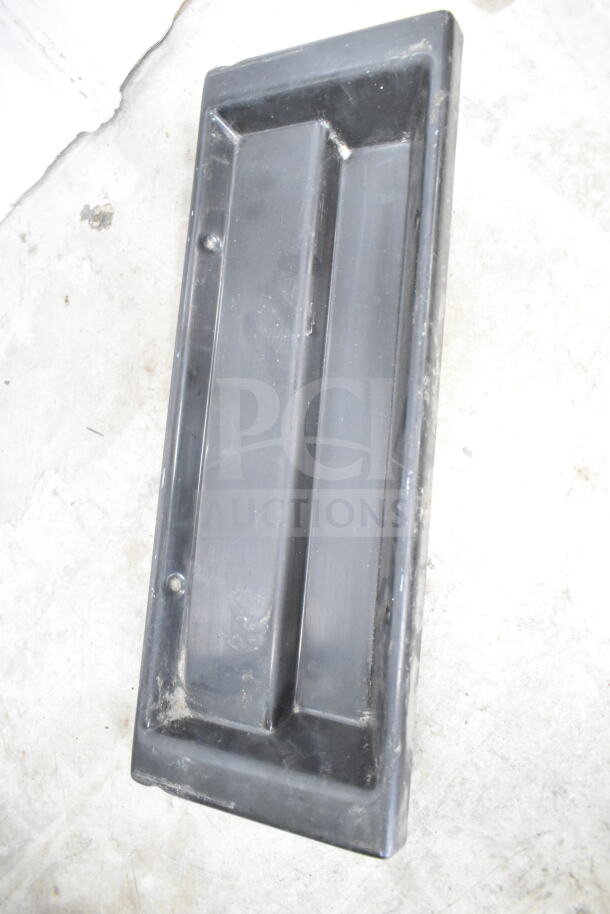 Black plastic tray, rectangular with raised edges, light scratches and signs of wear, set on concrete floor.