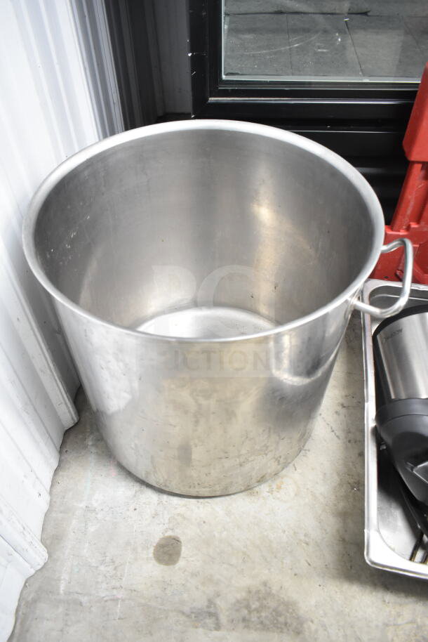 Stainless steel stock pot with handles, shown in used condition, part of a lot with various kitchen items.