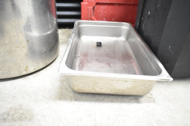 "Collection of kitchen items including a large stock pot and stainless colander, showing signs of use and wear."