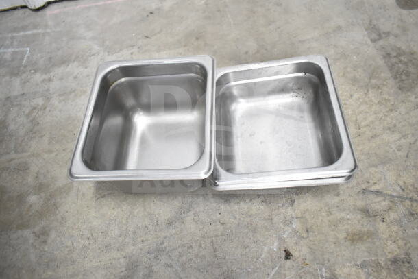 Stainless steel containers on a concrete surface, shown empty. Used condition with minor wear visible.