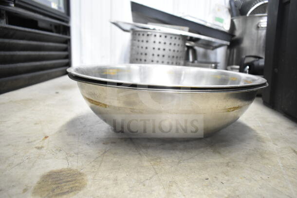 Lot of kitchen items including a stainless steel bowl, colander, stock pot, and china cap strainer on a countertop.
