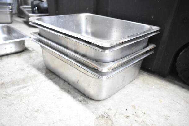 Stacked metal kitchen trays on the floor, part of an auction lot including various kitchen items. Slight wear visible.