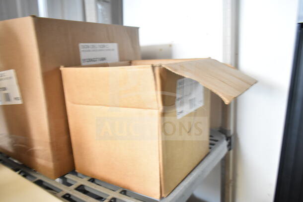 Cardboard boxes of brand new scratch and dent items including 512XKD105 deli tag inserts and 512XKD710BK write-on tags.