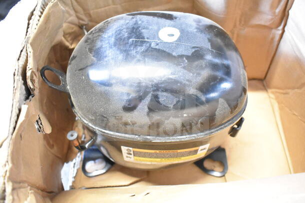 Embraco NT6222UV Compressor, 115V, 1 Phase, in box. Visible labels warn and caution for safe use. Dusty exterior.