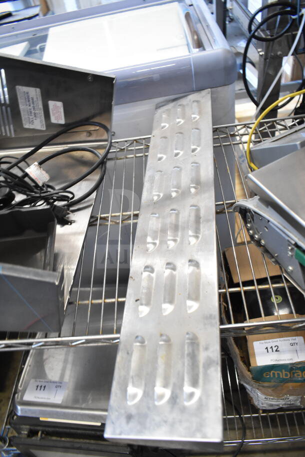 Various metal items on wire shelf, including vented panel and parts. Includes tags for identification. Auction lot of 9 items.