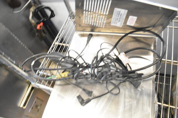 Assorted items including metal panels and cords on a metal shelf, suitable for industrial use.
