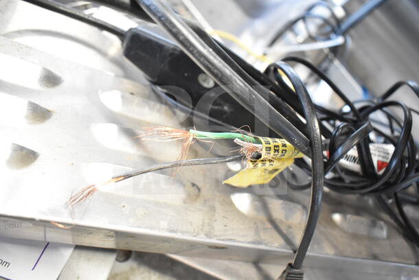 Nine assorted items including metal panels and cables, showing wear and exposed wires with visible labels and markings.