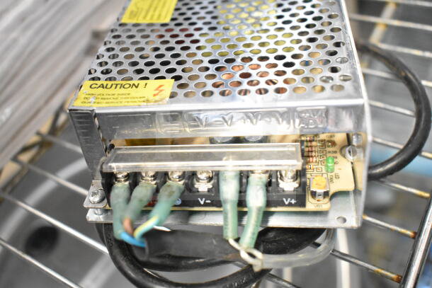 Electrical component with perforated metal casing, visible wiring, and caution label indicating high voltage.