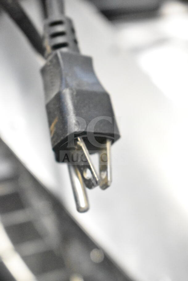 A close-up of a black power plug with visible wear, connected to a cord. Part of a lot with five auction items.