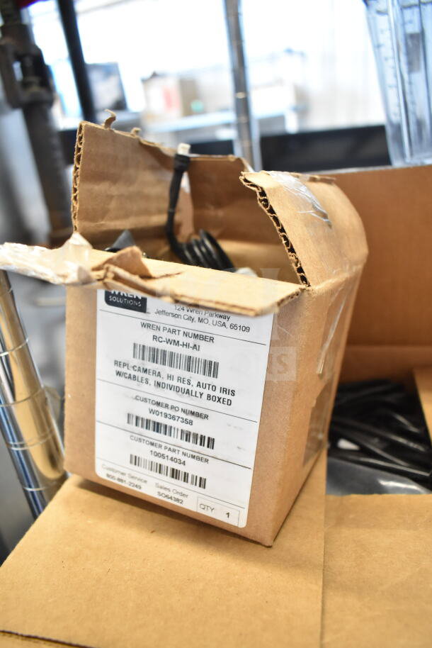 Cardboard box labeled "Wren Solutions" containing a Wren camera, high resolution, auto iris with cables, part number RC-WM-HI-AI.
