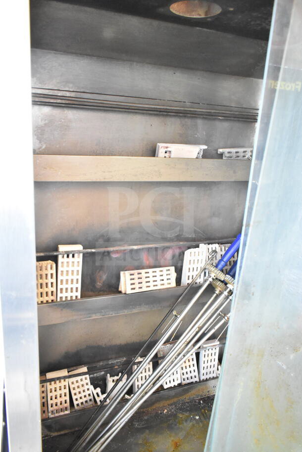 Attias commercial rotisserie oven with natural gas power, 70,000 BTU, on casters. Interior view shows shelves and rotisserie rods.