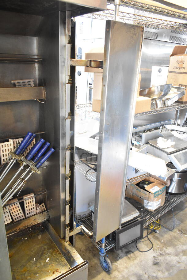 Attias commercial natural gas rotisserie oven, 70,000 BTU, on casters, used condition with internal racks and skewers visible.
