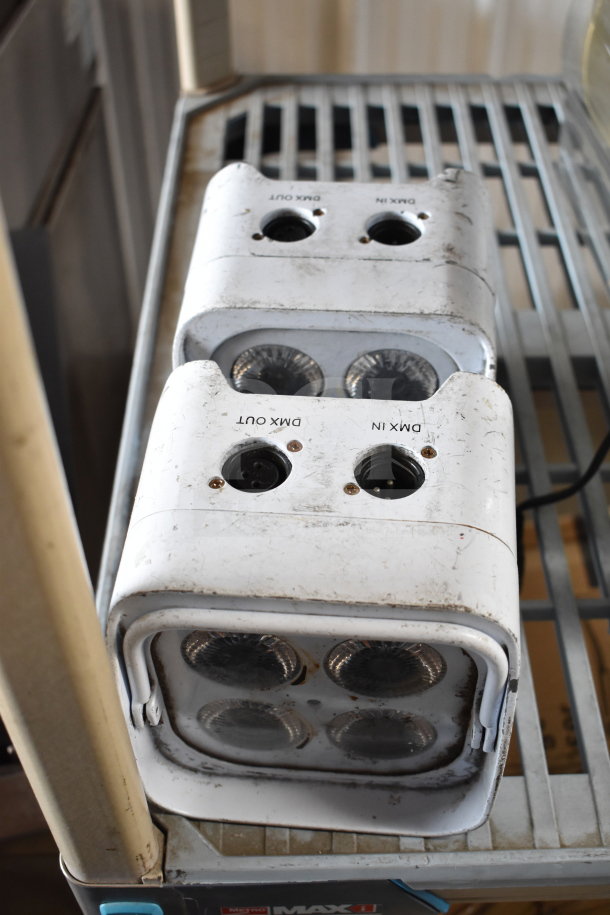 Leoch battery and two Rockville lights, mild wear, with visible DMX IN/OUT markings, on a metal shelf.