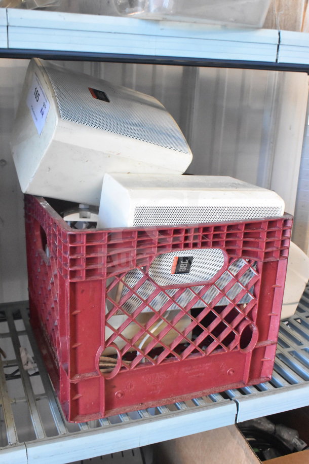 Four JBL Control 25AV speakers in a red crate, some wear visible. Ideal for audio installations.