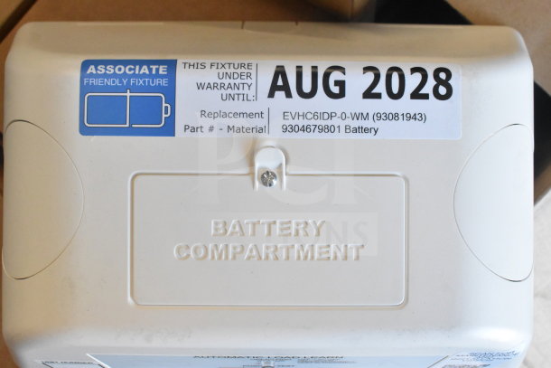 Box of items with Dual Lite EVHCEZP emergency light, warranty until Aug 2028, includes battery compartment label.