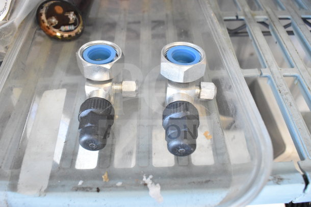 Two metal valves with blue inner rings and black knobs on a clear shelf, part of a 7-item auction lot.