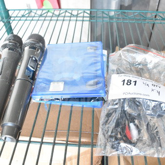 Two black microphones, a PS5 Madden 23 game case, and a sealed bag of cables on a metal shelf.