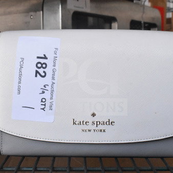 Kate Spade New York white purse with black strap, branded logo on front, attached auction tag, and metallic accents.