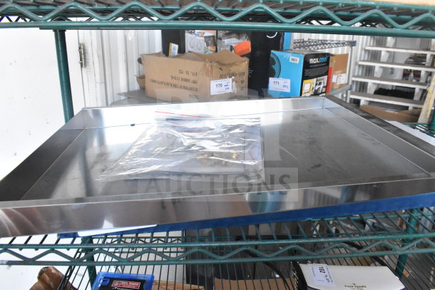 Metal bin on a shelf, includes a sealed plastic bag with contents. Good condition, visible shelf and boxes in background.