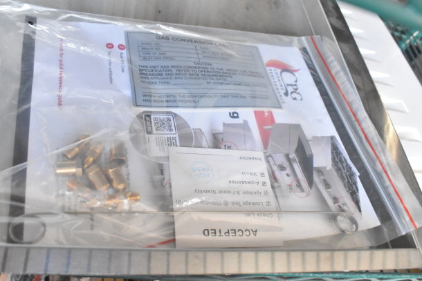 Bag with brass fittings and gas conversion labels. Includes inspection checklist and CPG manual, housed in metal bin.
