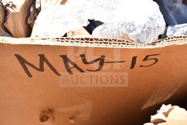 Cardboard box labeled "MAY-15" containing new scratch and dent items, including tabletops and table base columns.
