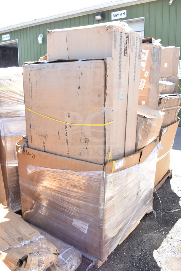 Stack of eight new scratch and dent items in cardboard boxes including a work table, wrapped on a pallet. Box labeled "MAY-21."