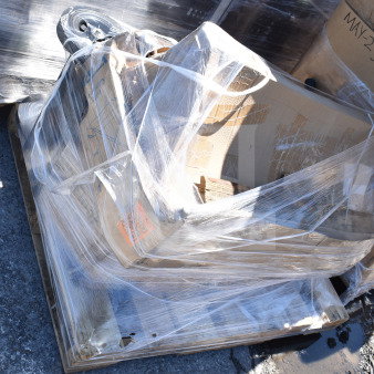 Four brand new scratch and dent items, including a trash cart, wrapped on a pallet. Boxes labeled "MAY23."