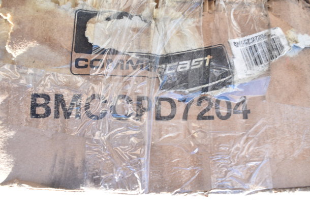 Cardboard box labeled BMC-GPD7204 from Comcast, wrapped in clear plastic, showing signs of damage.