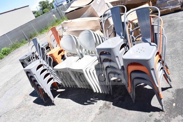 37 new scratch and dent chairs: gray and orange Tolix style, bar stools, white patio chairs. Auction lot, outdoors.
