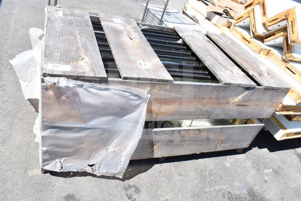 Stack of 10 brand new scratch and dent doors in a wooden crate, partially covered in plastic wrap, ready for auction.