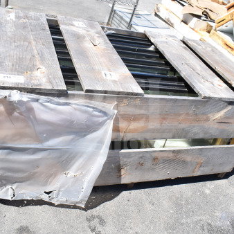 Stack of 10 brand new scratch and dent doors in a wooden crate, partially covered in plastic wrap, ready for auction.