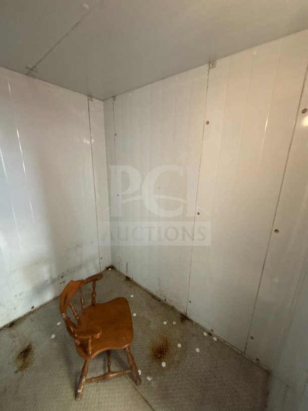 Master-Bilt 8'x12' walk-in box interior showing wear, white panel walls, and a wood chair on the floor. No visible labels.