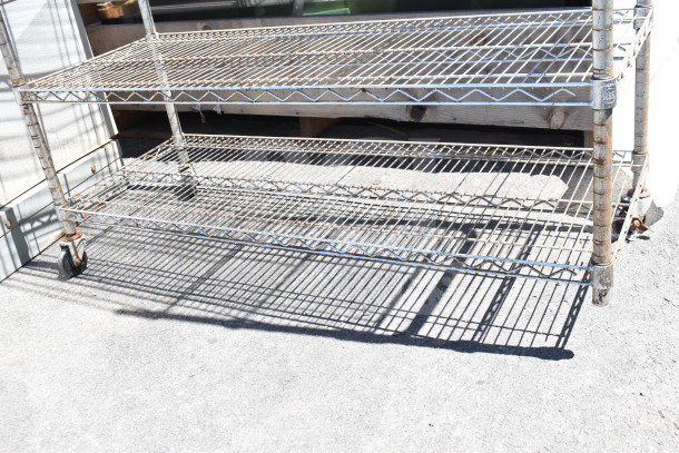 Chrome finish 5-tier wire shelving unit on casters, missing one caster, needs dismantling, suitable for freight shipping.