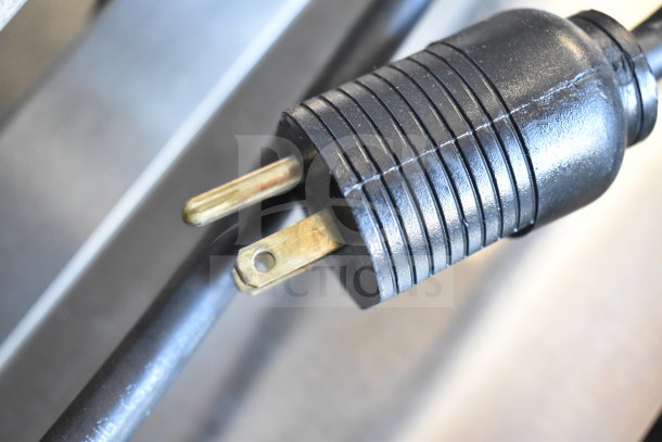 Close-up view of JBT 2ND-GEN-MFJ citrus juicer's power plug. Black, two-prong with rounded casing.