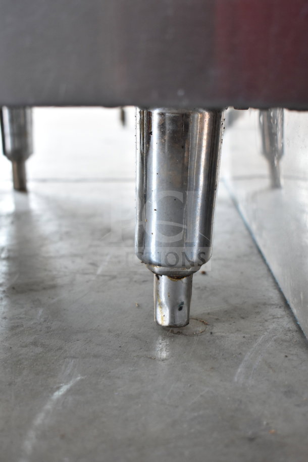 Bakers Pride commercial gas deep fryer leg detail, stainless steel construction, sturdy floor style, some wear visible.