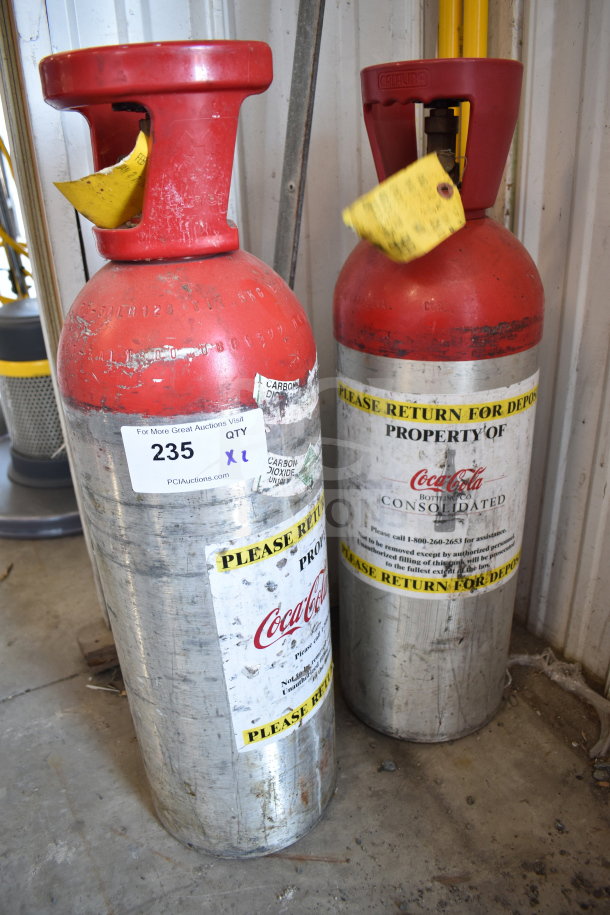 Two metal CO2 tanks labeled "Property of Coca-Cola," with red tops and deposit return stickers. Buyer pickup required.