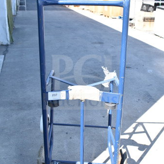 Blue furniture dolly with handles and wheels, showing moderate wear. Tag marked "237" attached on frame.