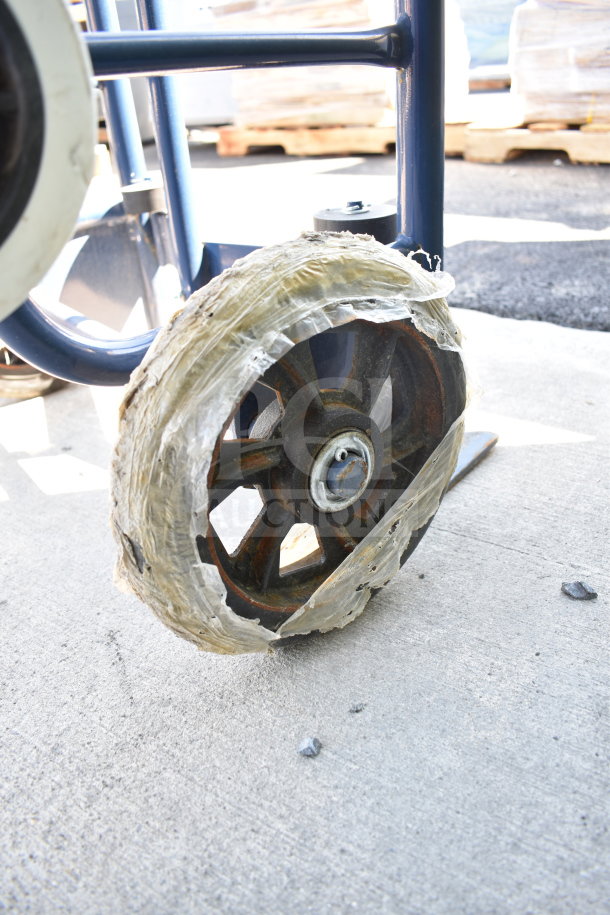 A blue furniture dolly with a worn wheel wrapped in plastic tape, showing some rust. Suitable for heavy loads.