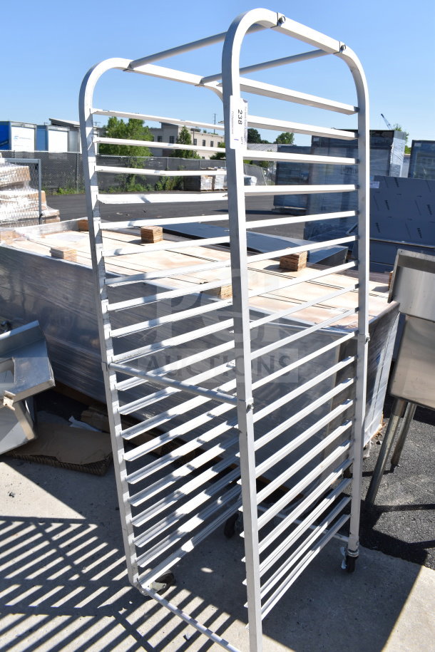 Commercial pan transport rack on casters, metal construction, multiple tiers, outdoor setting, item tag visible.
