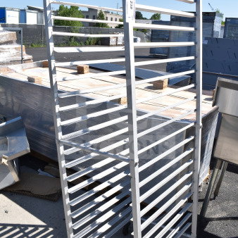 Commercial pan transport rack on casters, metal construction, multiple tiers, outdoor setting, item tag visible.