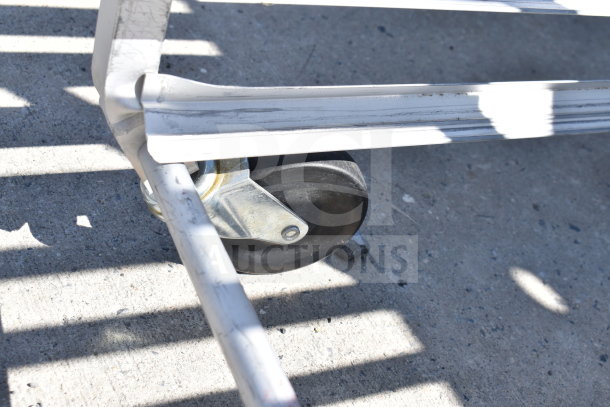 Commercial pan transport rack with sturdy casters, steel frame, outdoors in used condition; ideal for kitchen use.