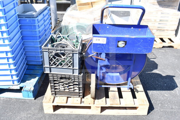 Pallet lot with banding station, crate of cords, and blue cart. Visible tags indicate quantity as "Pallet 1."