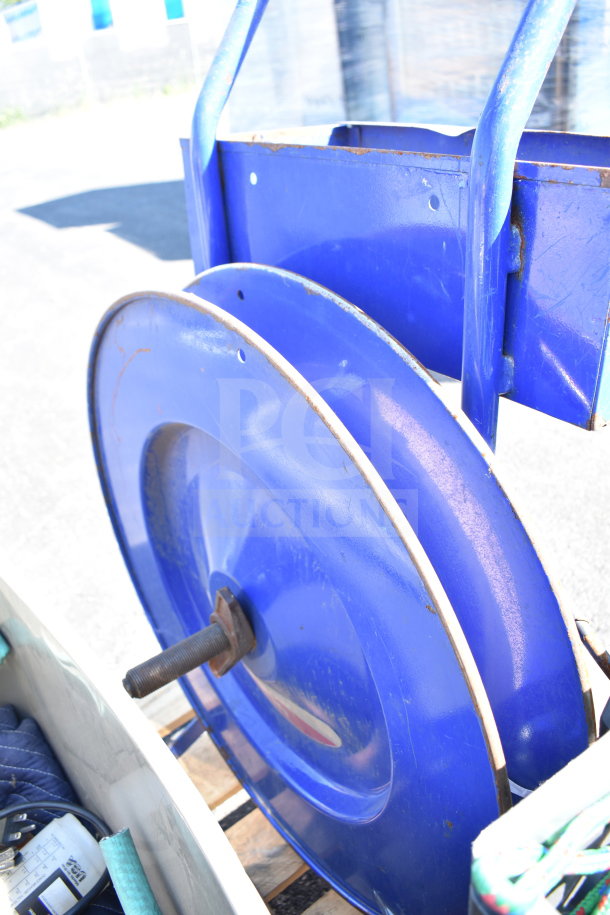 Pallet lot featuring a blue banding station with reel and cords. Good condition for industrial use.